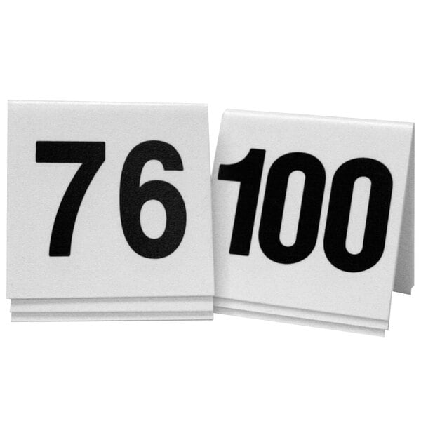 Two white Cal-Mil table tents with black numbers on a white surface.