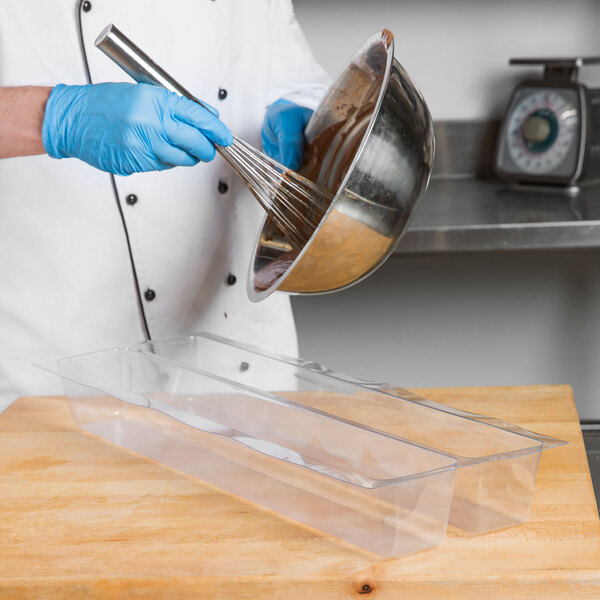 A person in a white coat mixing chocolate in a bowl.