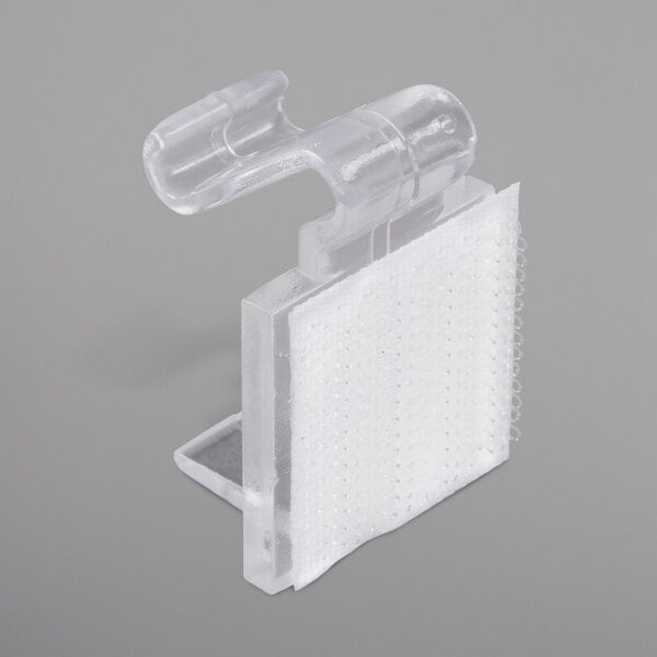 A Snap Drape clear plastic table skirt clip with white hook and loop attachment.