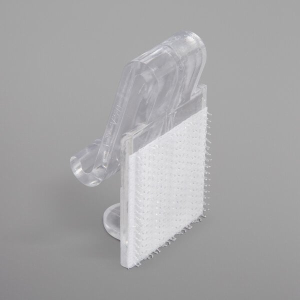 A clear plastic Snap Drape table skirt clip attached to a table.