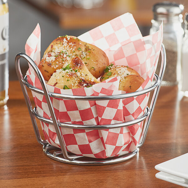 A Clipper Mill chrome plated metal round bucket basket on a table filled with food.