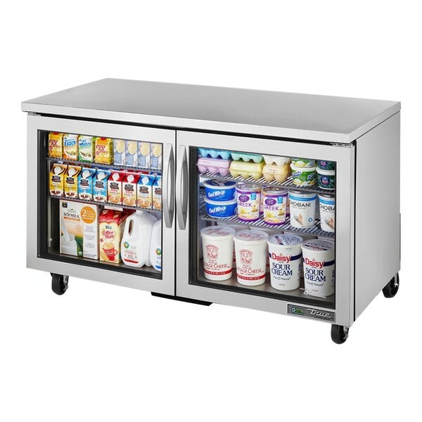 A True undercounter refrigerator with glass doors filled with dairy products.
