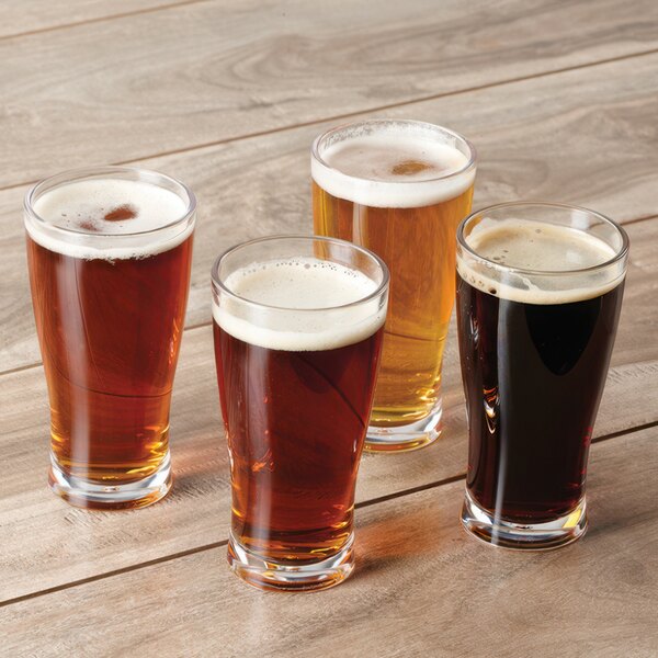 A group of GET customizable plastic dessert shot glasses filled with beer on a wooden table.