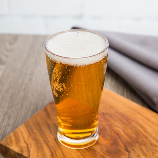 A GET customizable plastic dessert shot glass filled with beer on a wooden surface.