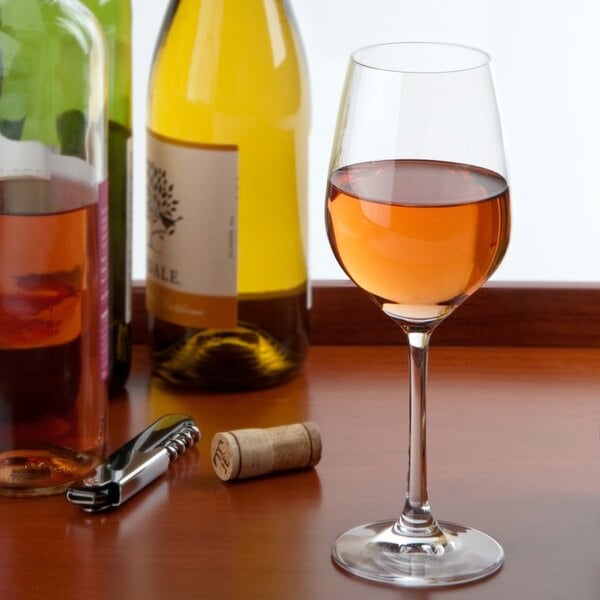 A Stolzle white wine glass on a table next to a bottle of wine.