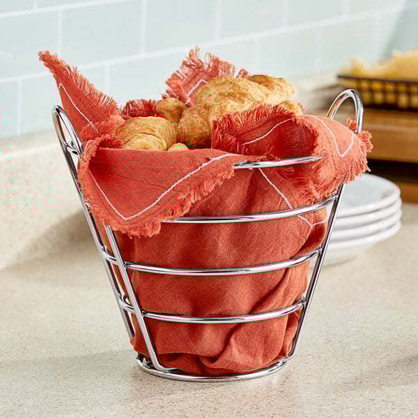 A Clipper Mill stainless steel round wire bucket basket holding croissants on a counter.