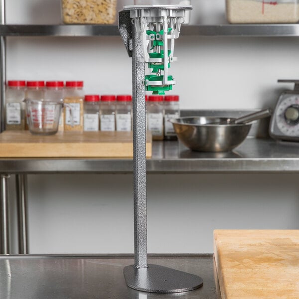 A Tellier manual cucumber peeler in a metal stand with green accents.