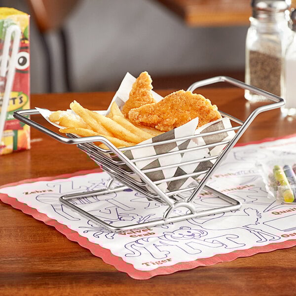 A metal basket with chicken and french fries on a table.