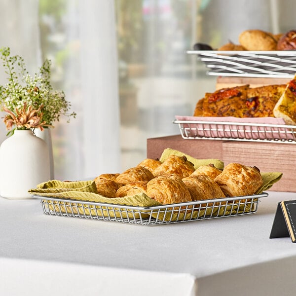 A Clipper Mill stainless steel square wire grid basket holding pastries on a table.