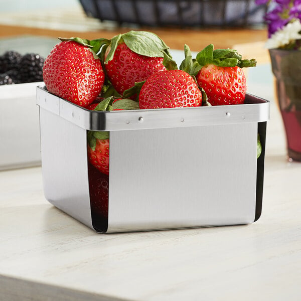 A stainless steel Clipper Mill square berry basket filled with strawberries.