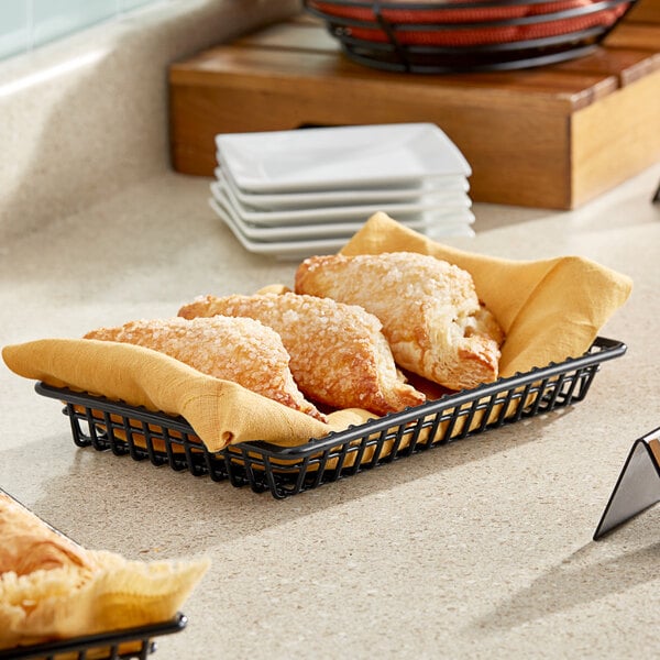 A black rectangular iron grid basket filled with pastries on a counter.