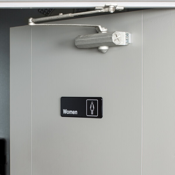 A restaurant bathroom door with a Vollrath Traex women's restroom sign on it.