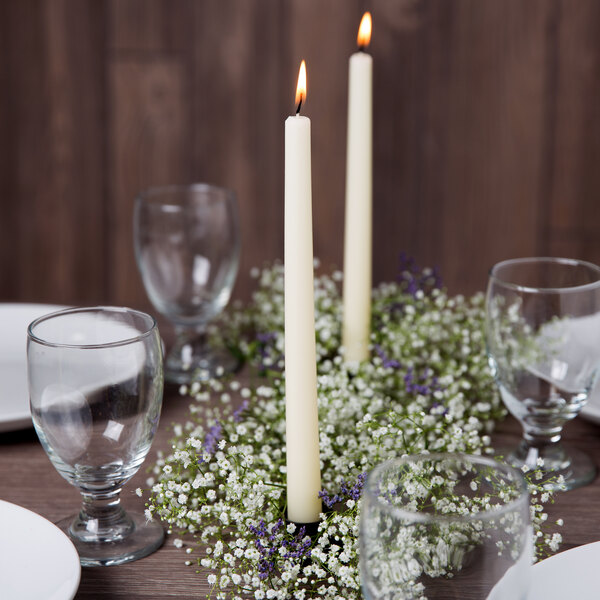 A table set with Hyoola ivory taper candles in a wreath of white flowers.
