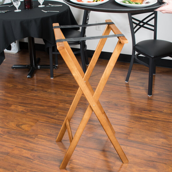 An American Metalcraft walnut wood tray stand holding plates on a table with a black tablecloth and silverware.