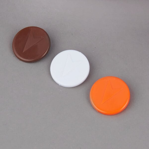 Three different colored plastic tabs: white, orange with a lightning bolt, and brown with an arrow.