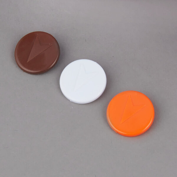 A gray surface with three round buttons: one white, one orange, and one brown, each with a different symbol.