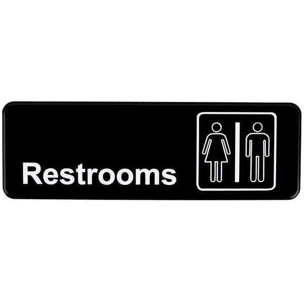 A black Vollrath Traex restroom sign with white text and symbols.