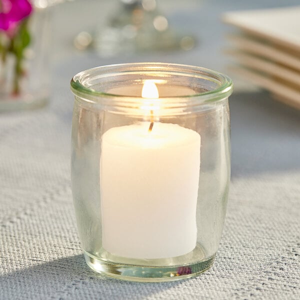 A Leola white votive candle in a glass jar.