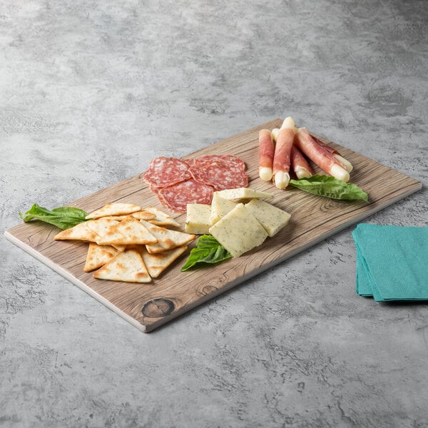 A Thunder Group Sequoia Faux Wood Melamine serving board with meat and crackers on it.