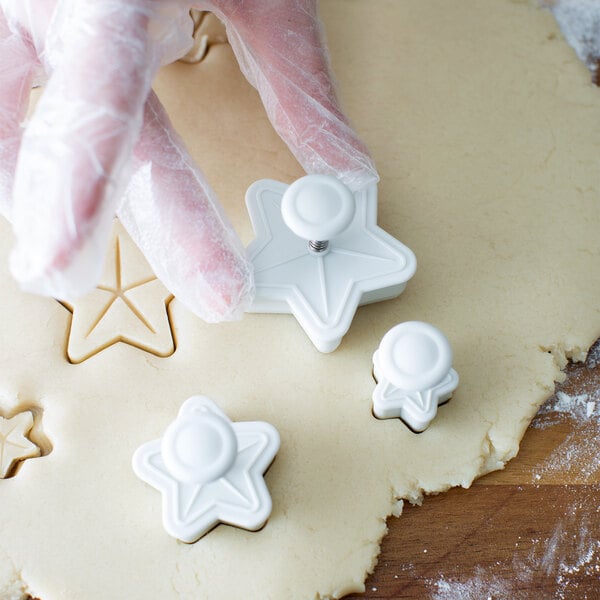 a person's hands in gloves cutting out cookies