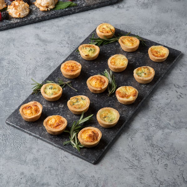 A tray of mini quiches with herbs on a Thunder Group Onyx Faux Marble melamine serving board.