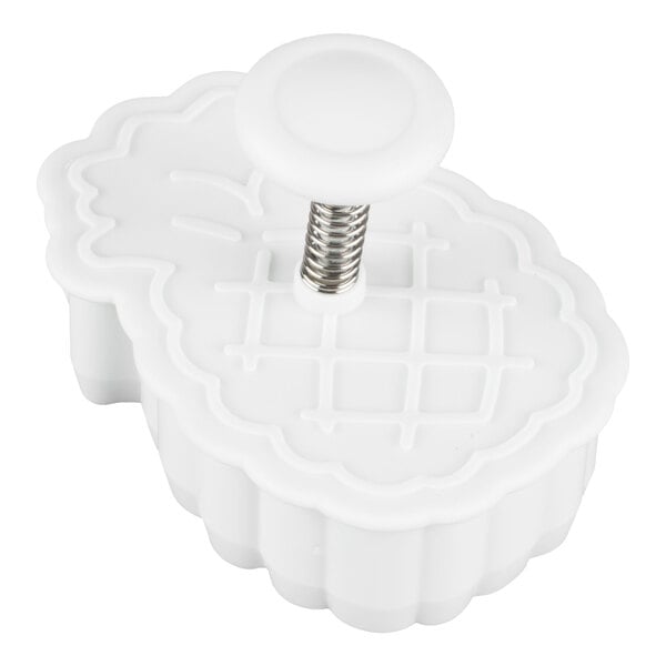 A white plastic plunger cutter with a pineapple-shaped design and a spring-loaded handle.