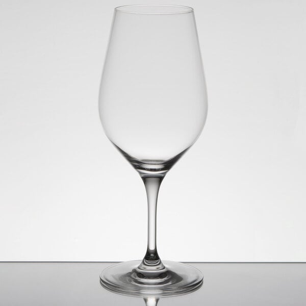 A clear Chef & Sommelier Bordeaux wine glass on a table with a reflection.
