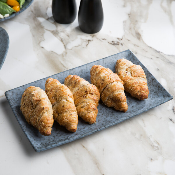 A rectangular blue stoneware platter with croissants on it.
