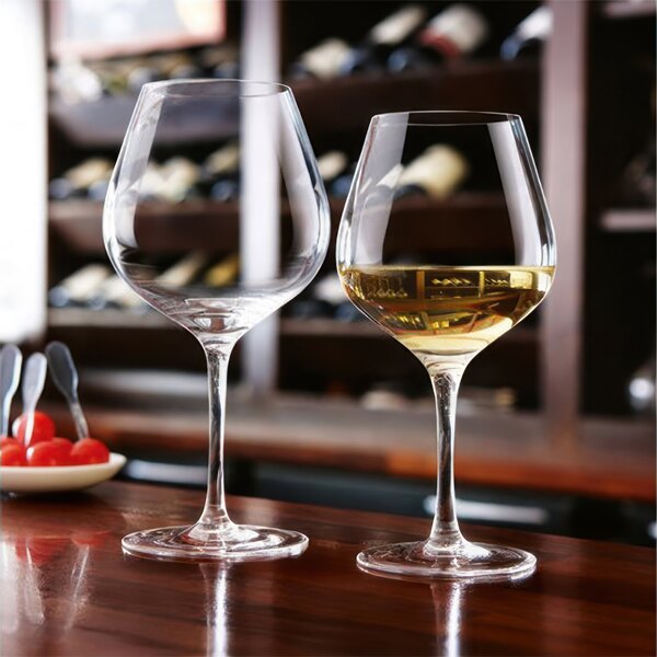 Two Chef & Sommelier Cabernet wine glasses on a table with a bottle of wine.
