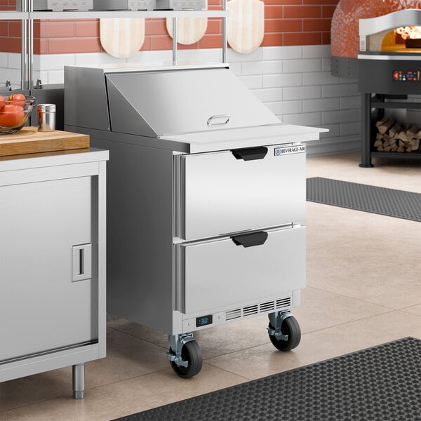 A stainless steel 2-drawer mega top refrigerated sandwich prep table on wheels.