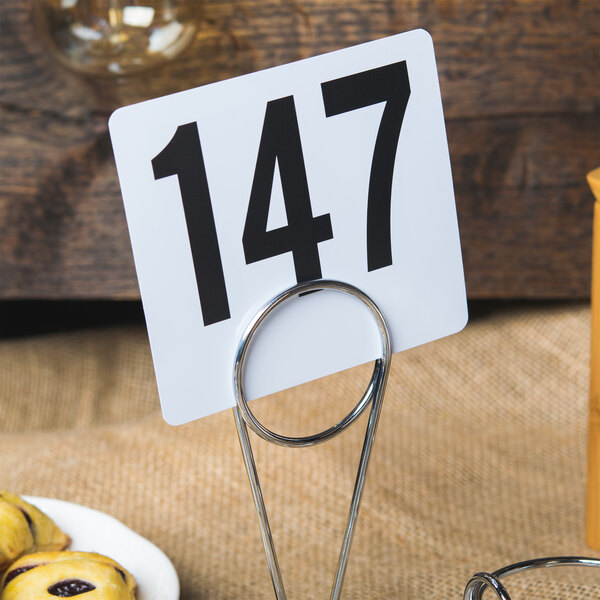 A Clipper Mill 2-compartment condiment caddy with a number holder on a table with food plates.