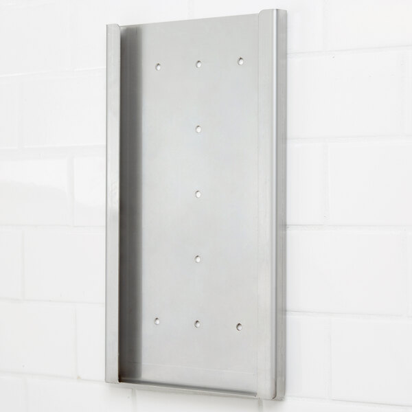 A stainless steel wall mount bracket with holes on a white tile wall.