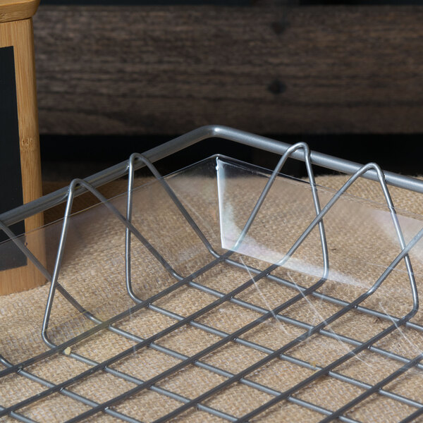 A Clipper Mill clear plastic basket liner on a metal tray in a bakery display.