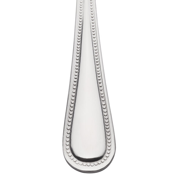 A close-up of a 10 Strawberry Street Pearl stainless steel serving spoon with a beaded handle.