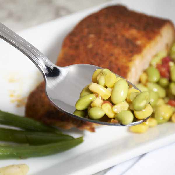 A 10 Strawberry Street stainless steel serving spoon with beans and green beans on it.