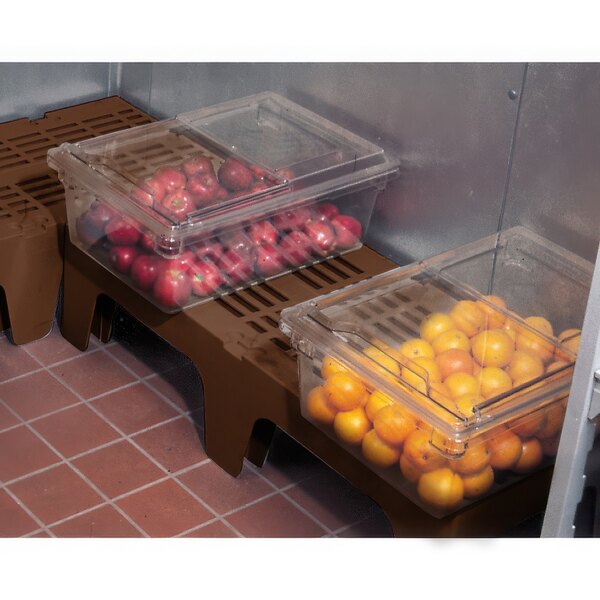 A Cambro brown slotted top dunnage rack holding plastic containers of oranges and apples.