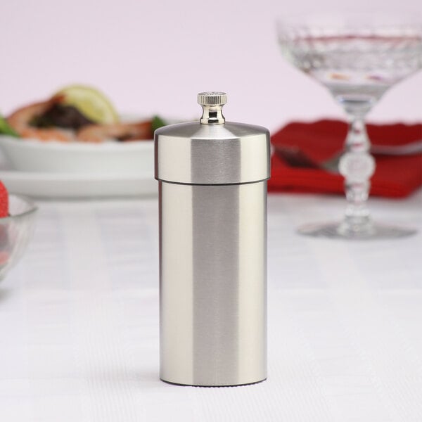 A silver stainless steel salt mill on a white table.