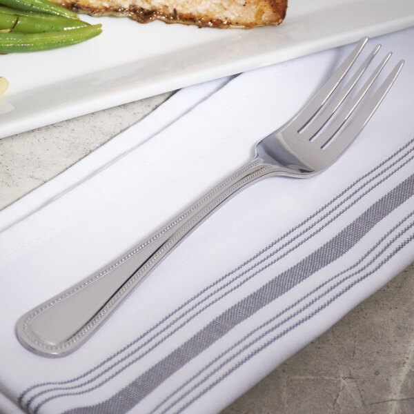 A 10 Strawberry Street Pearl stainless steel dinner fork on a white plate.