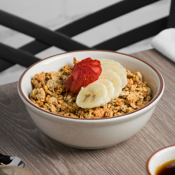 A Tuxton brown speckle nappie bowl filled with cereal and fruit with a spoon.