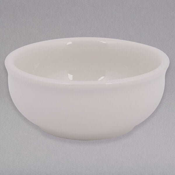 A Tuxton eggshell white china sauce dish.