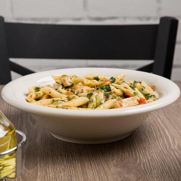 A Tuxton eggshell china pasta bowl filled with pasta on a table.