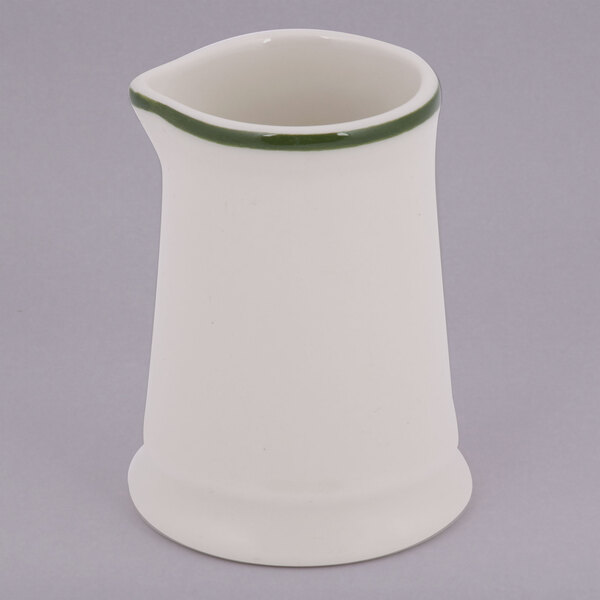 A white Tuxton china creamer with a green band.