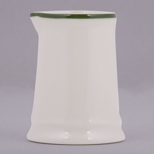 A white rectangular Tuxton China creamer with a green band on the top.