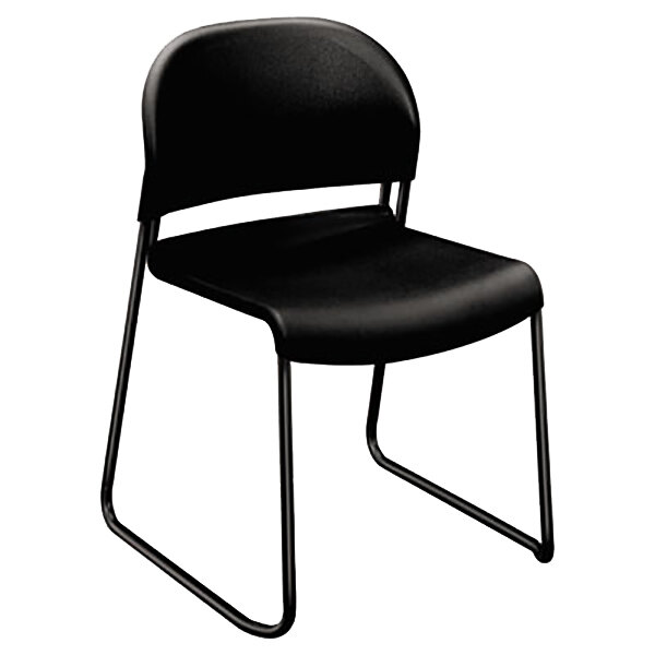 A close-up of a HON GuestStacker black plastic chair with metal legs.