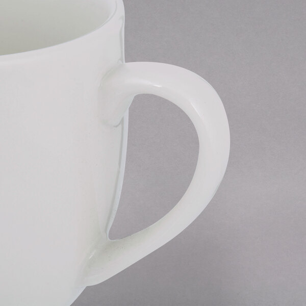 A close-up of a white Tuxton Milano mug with a white handle.
