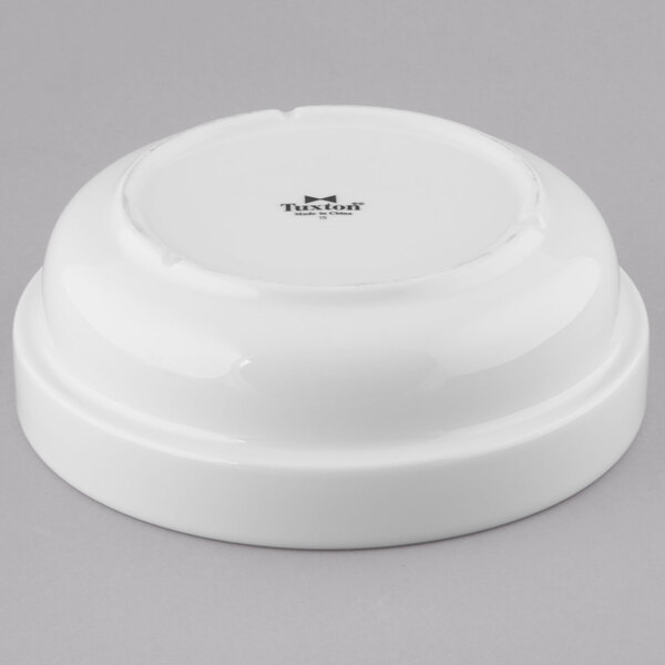 A stack of white Tuxton porcelain salad bowls with a logo on them.