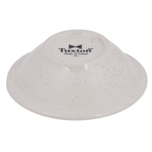 A white Tuxton narrow rim fruit bowl with black speckles and a black logo.