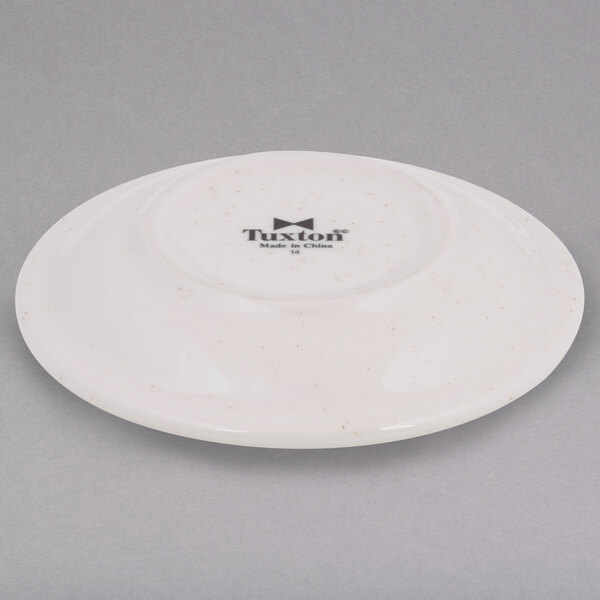 A Tuxton brown speckle china saucer with black text on it.