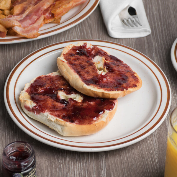 A Tuxton brown speckle narrow rim china plate with a piece of bread and jam on a table.