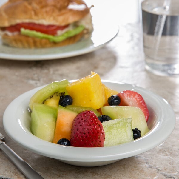 A Carlisle Sierrus bone melamine bowl filled with apples on a table.